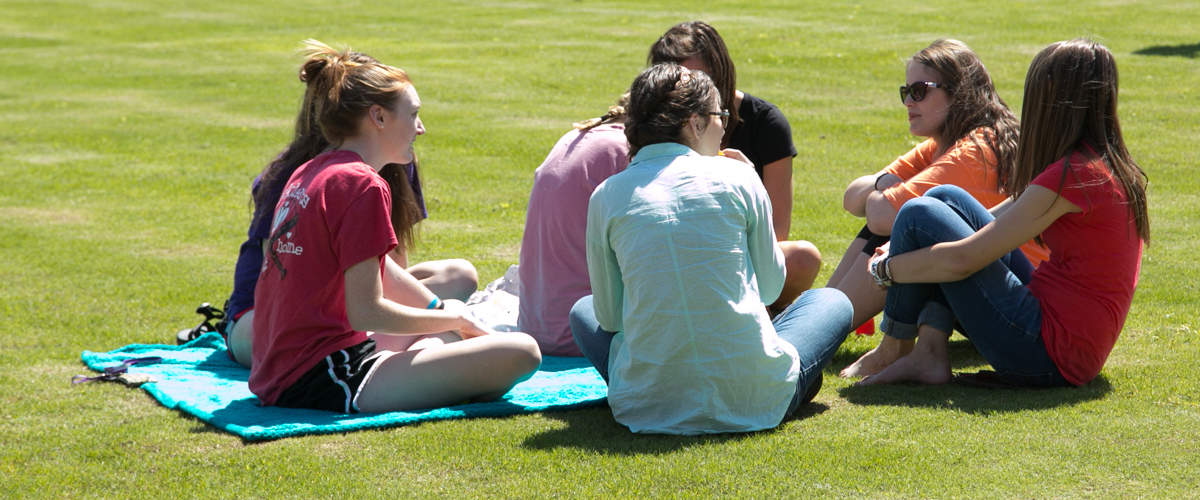 students relaxing on green space.