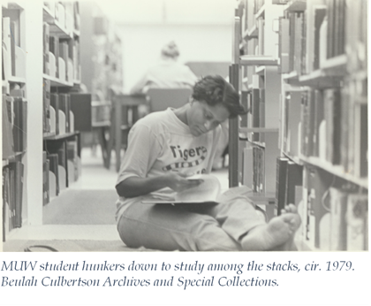 black and white image of a student studying barefoot in the stacks circa 1979