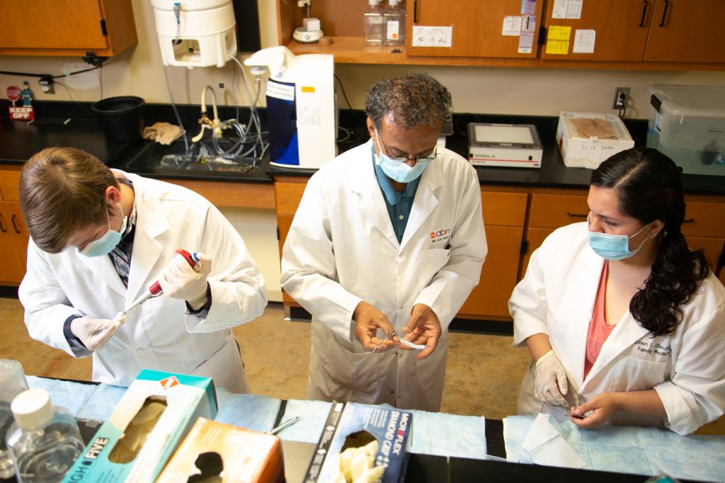Students wearing masks and lab coats in research lab