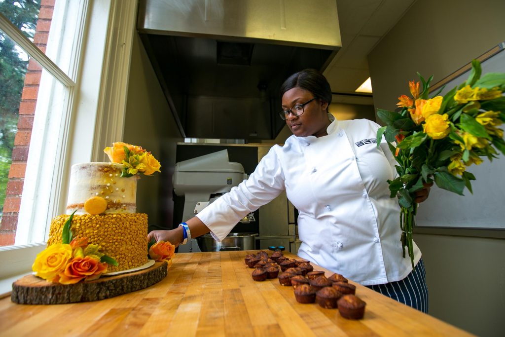 Female culinary student place flowers near a cake
