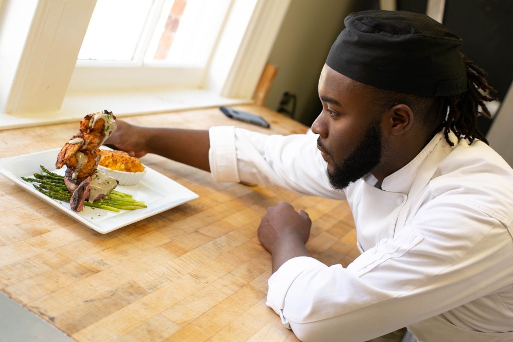 male culinary student plates a dish