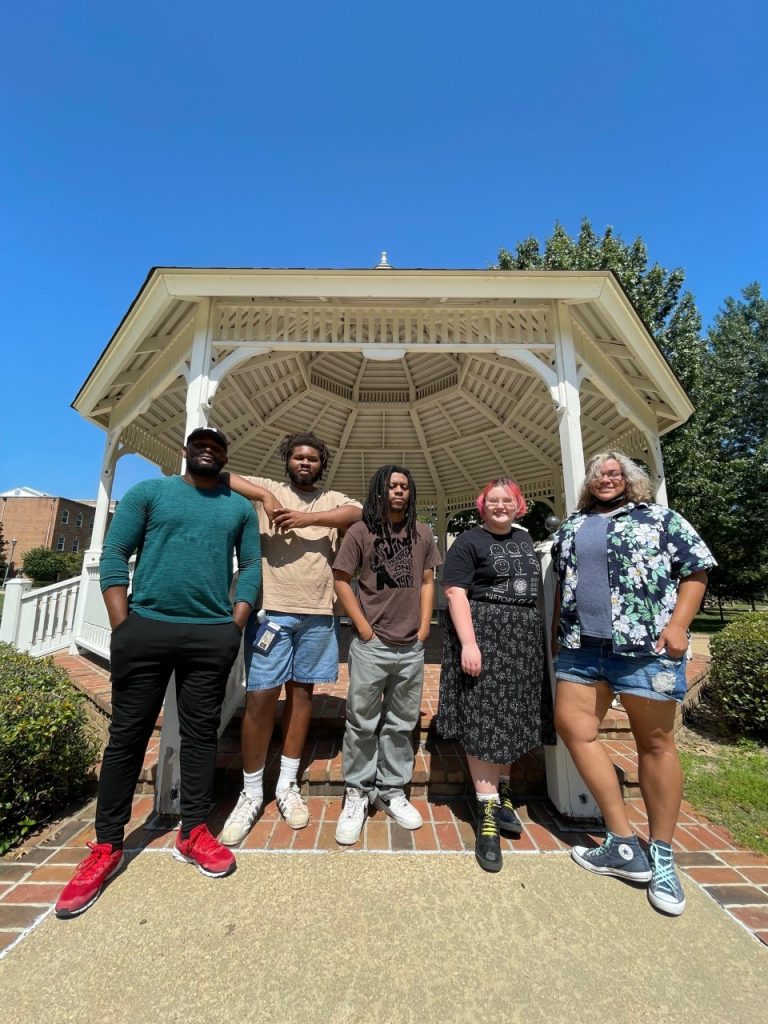 five artists stand outside near the campus gazebo