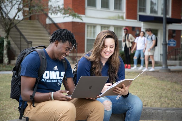 Man and woman study outdoors with laptop