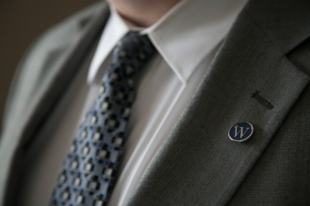 Close up of a man in a suit with a W lapel pin
