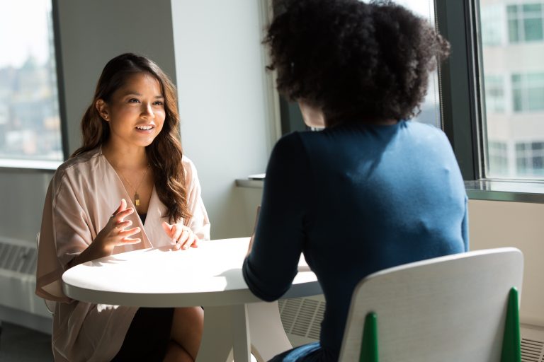 Two women chat next to a window during an interview