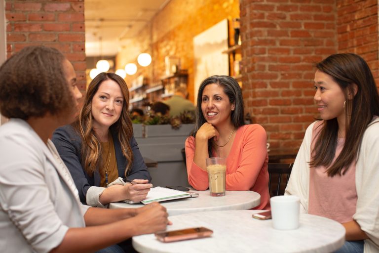 four women holding a meeting in a cafe