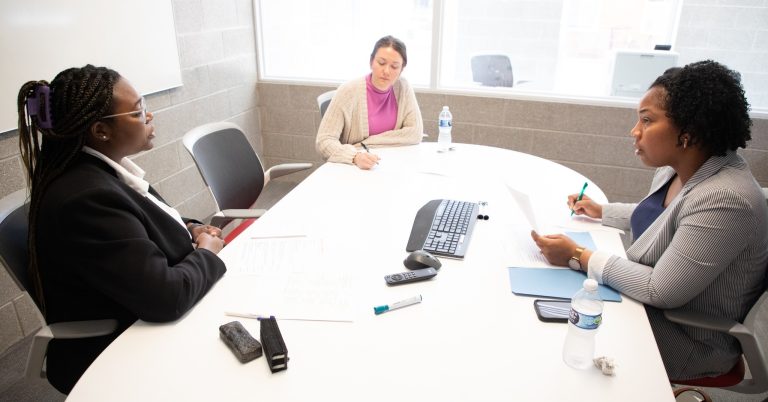 Photo of a W student interviewing with two employer representatives.