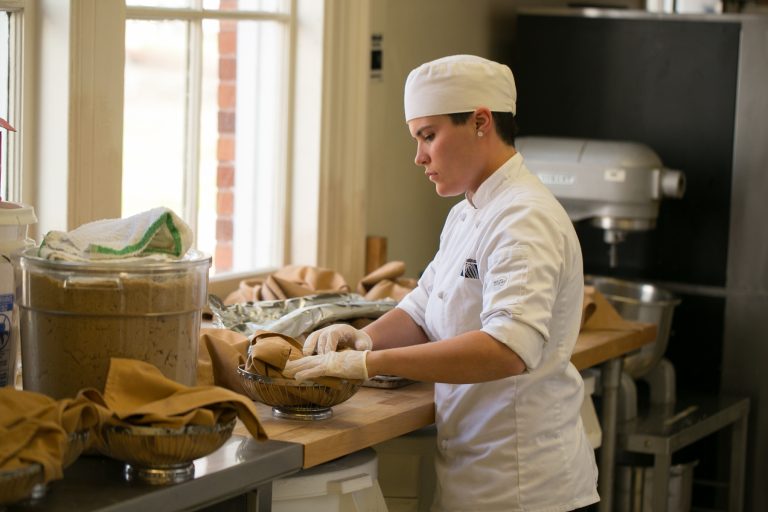 A student chef carries a basket of breads