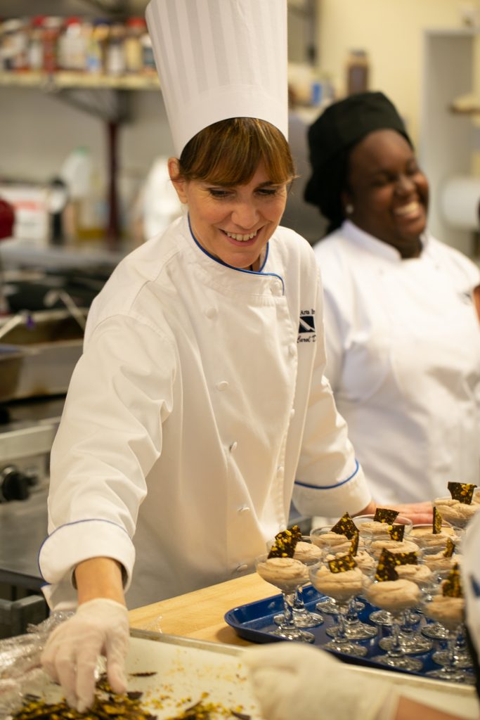 Two female student chefs arrange desserts in the kitchen