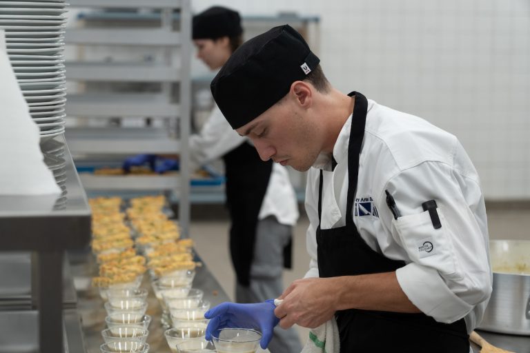 A student chef prepares an arrangement of cups.