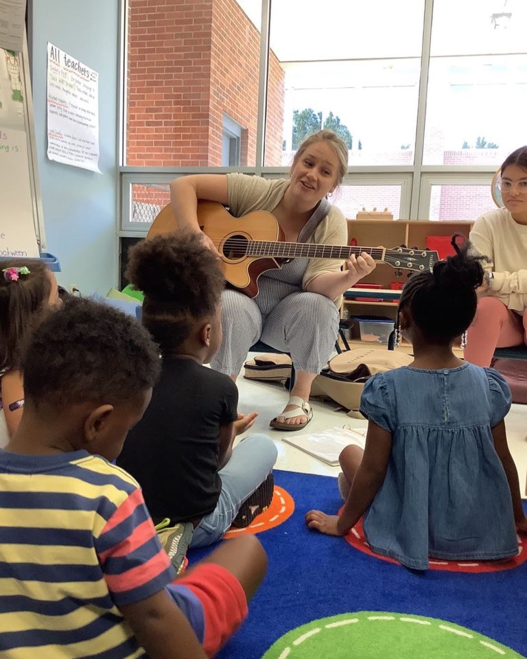 A teacher plays a guitar for class of preschool students