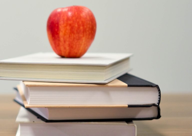 An apple on top of stack of textbooks