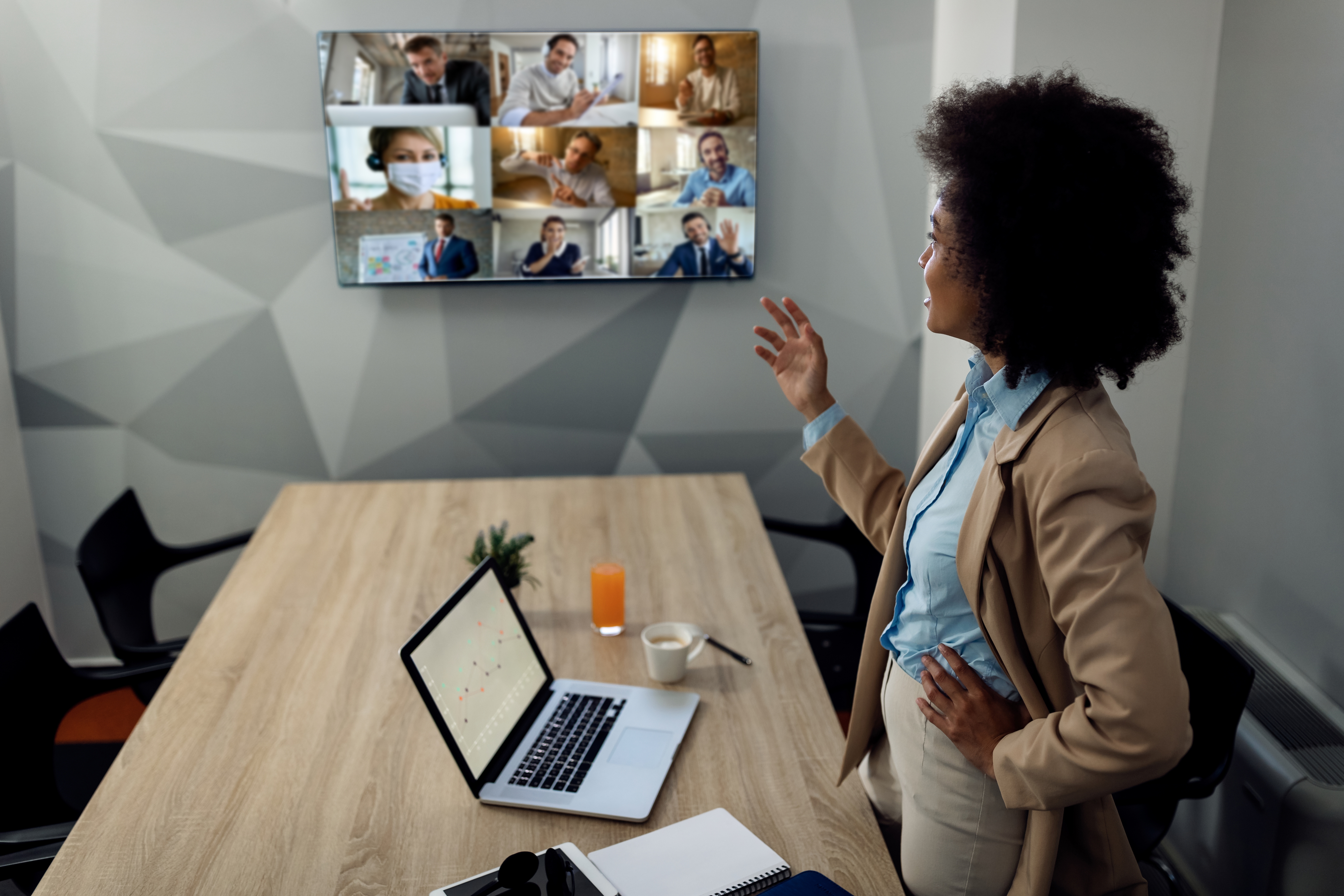 African American businesswoman talking to her team while holding online meeting via conference call from the office.