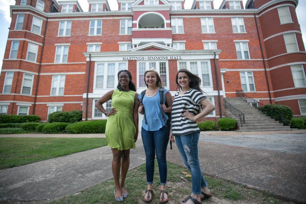 Three women stand in front of Hastings-Simmons Hall