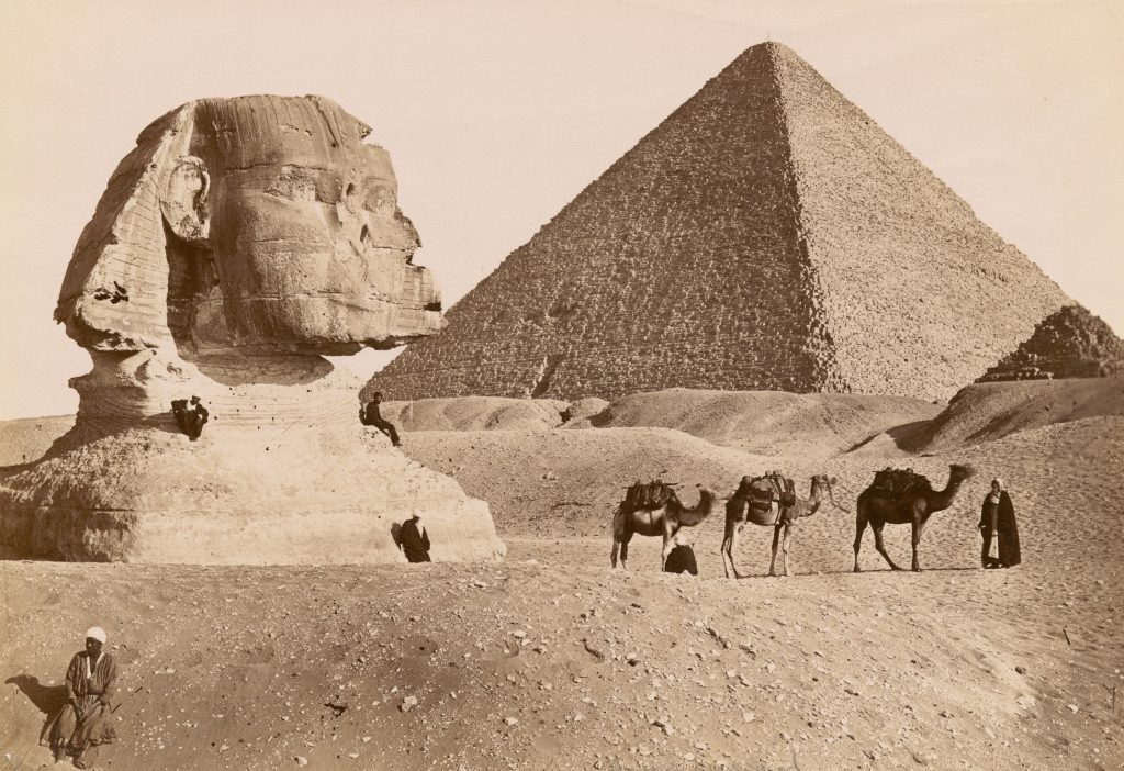 Historic photo of the Pyramid of Giza and Sphinx with camels in the foreground.