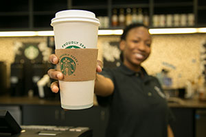barista holding a coffee toward camera