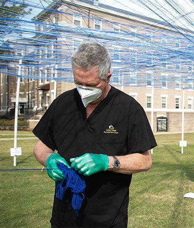 Dr. Walt Starr in scrubs outside with strings above head