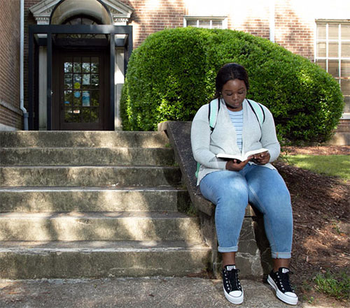 female student reads outside Painter Hall