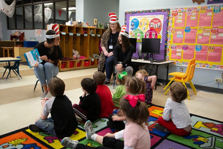 three female students read to pre-k class