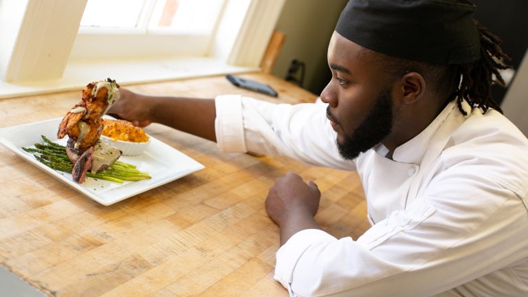 Male student chef plates a dis