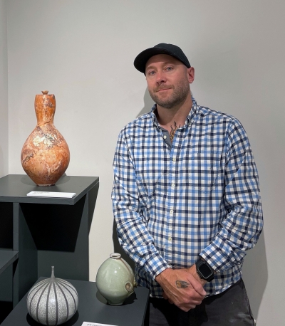 Man standing next to three vases