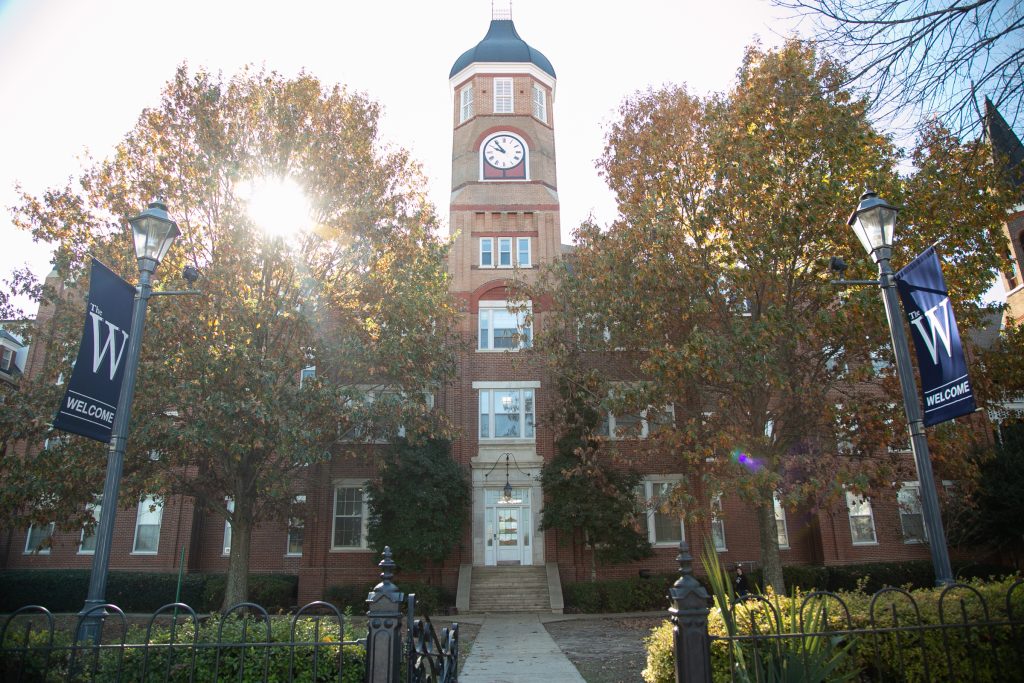 Sun rays burst through the trees in front of historic Callaway Hall