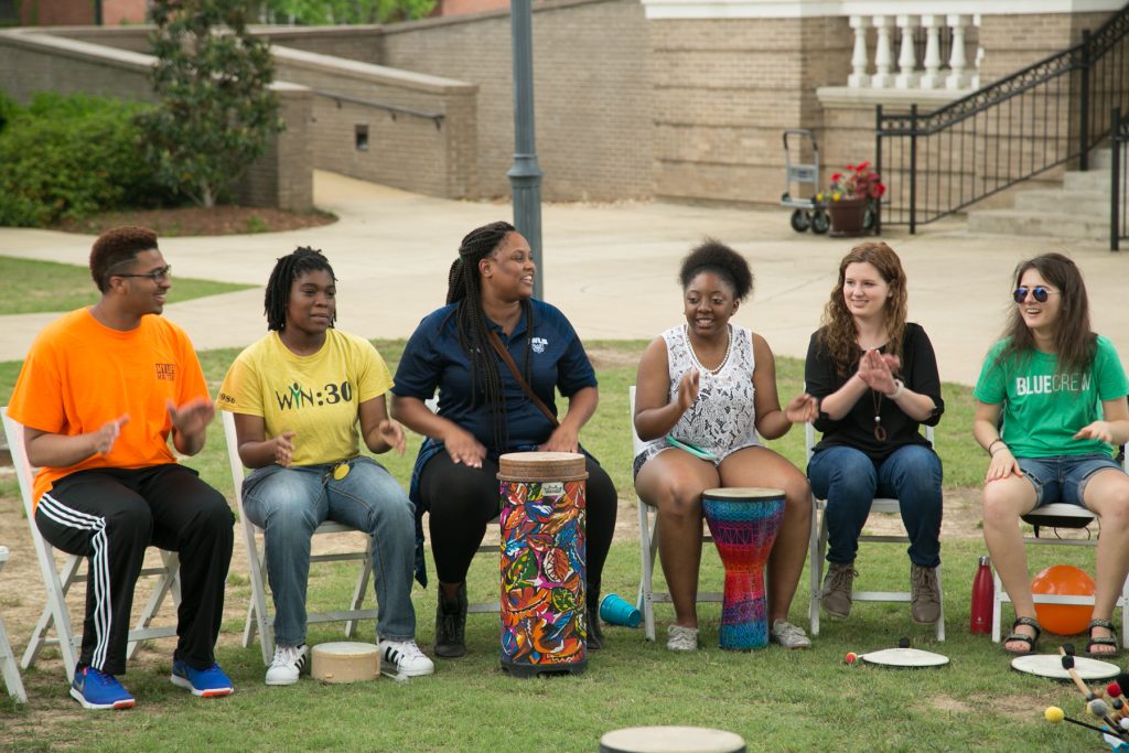 Students sit in a drum circle outdoors