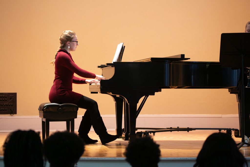 A woman plays a piano on stage.