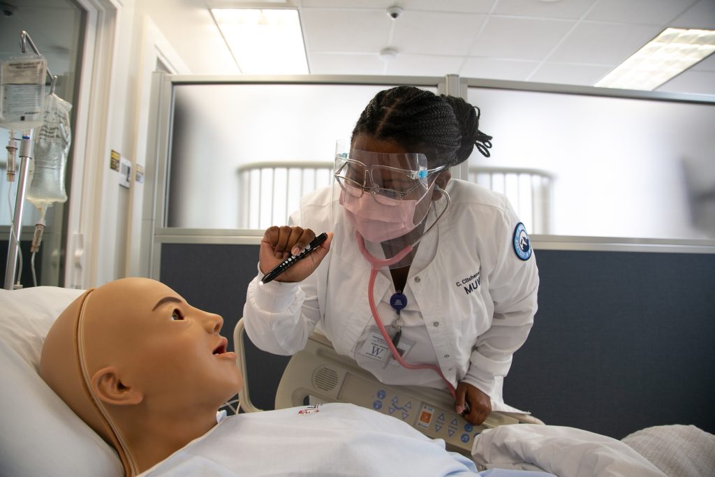 A student works with a simulated patient