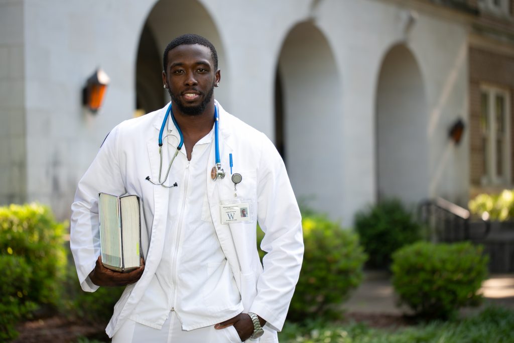 Male student nurse holding text books outdoors