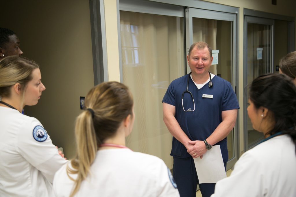 A professor and nursing students in the skills lab