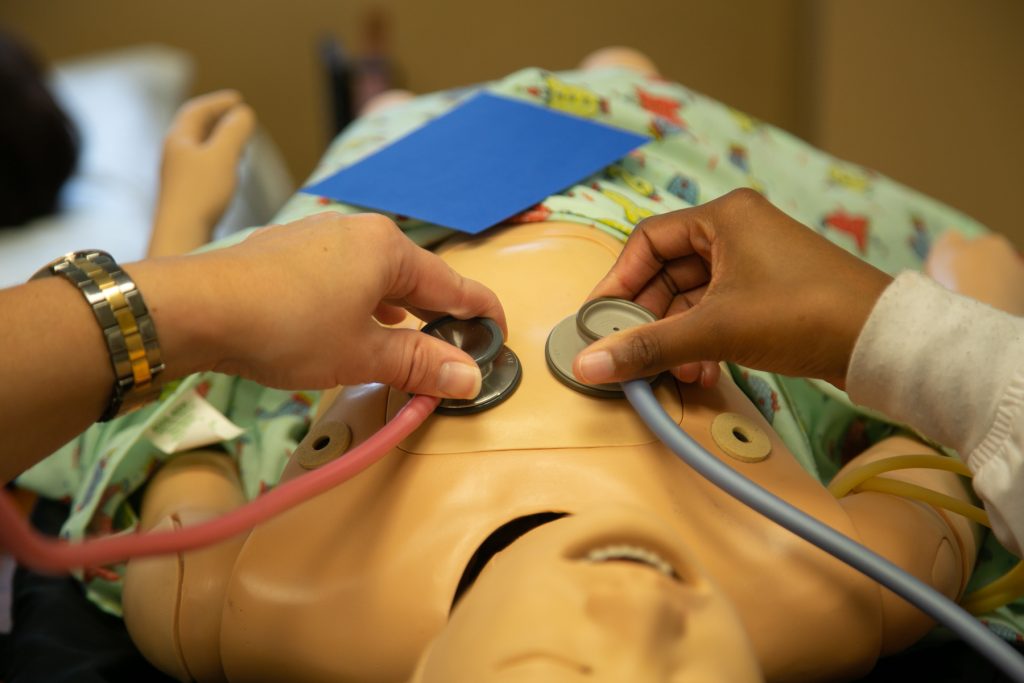 Two nursing students work on a simulated patient