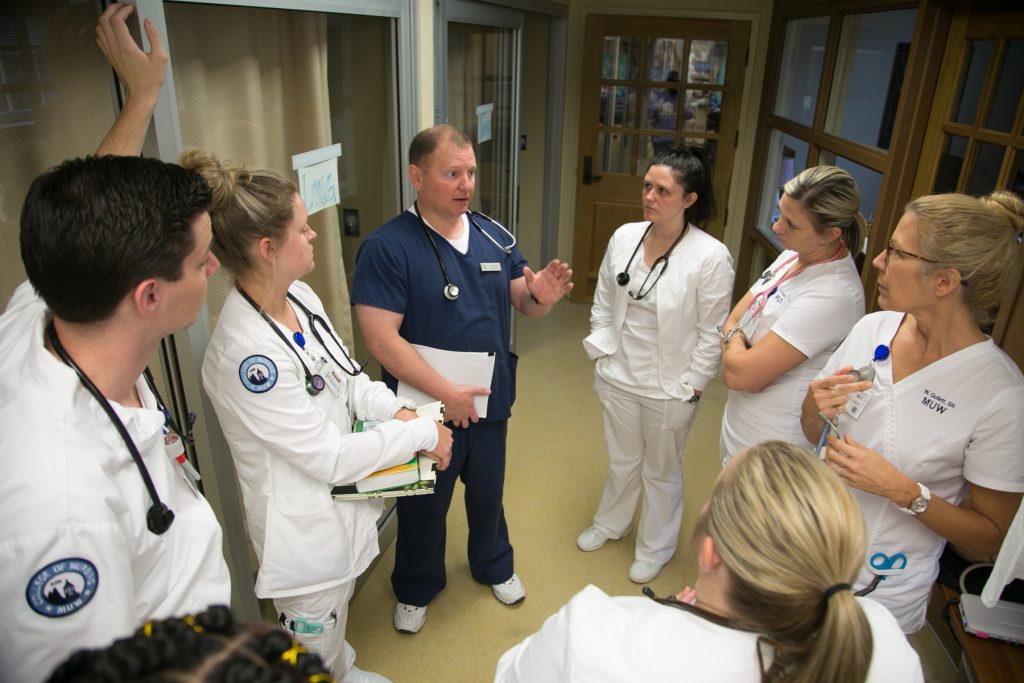 A professor and nursing students in the skills lab