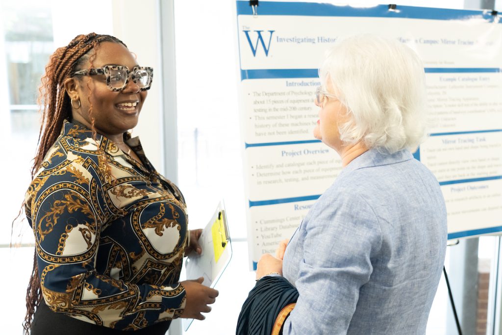 Female student presents her poster on psychology research to an MUW alumna