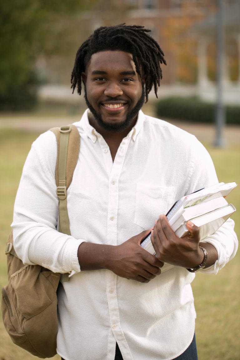 Man holds textbooks outdoors