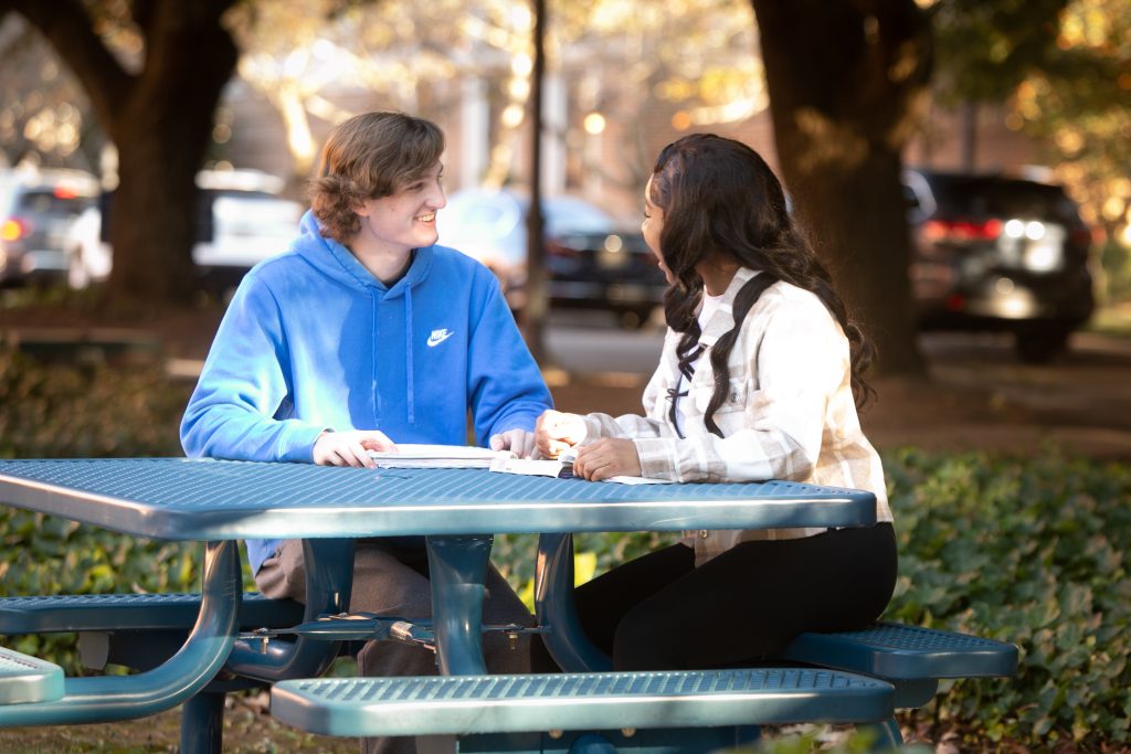 students sit at table outdoors
