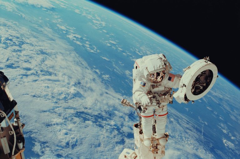 An astronaut takes part in an EVA with the Earth in the background