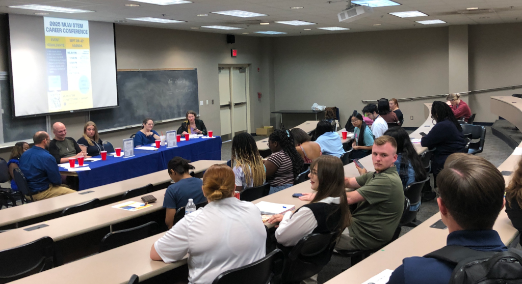 Panelists in front of a classroom of students.