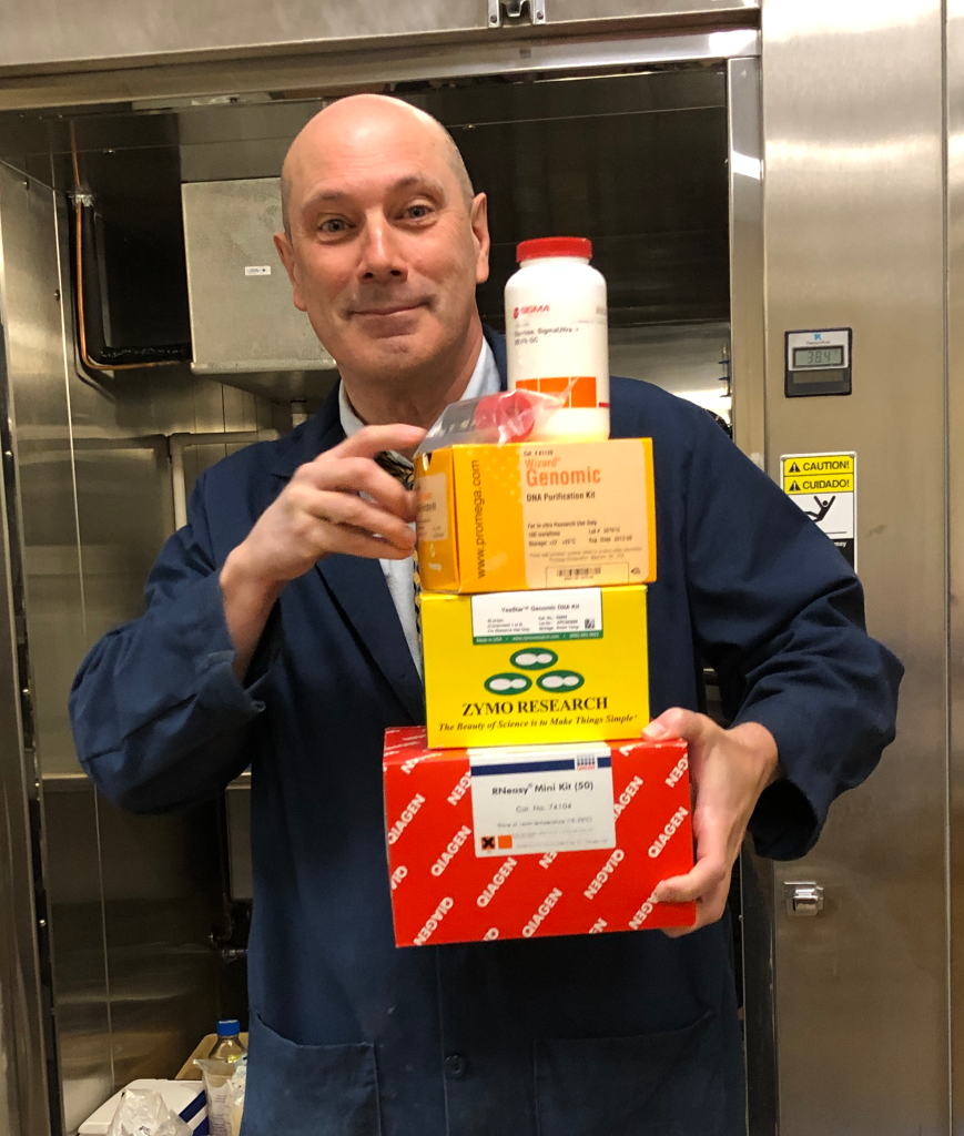 Faculty member holding a stack of new lab reagents.