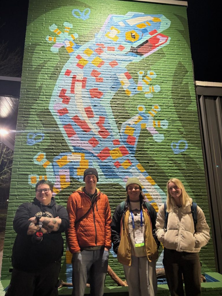 Kane Petty, Dr. Travis Hagey, Maddie Guerin, and Brooklyn Ward stand by a gecko mural in Portland, OR.