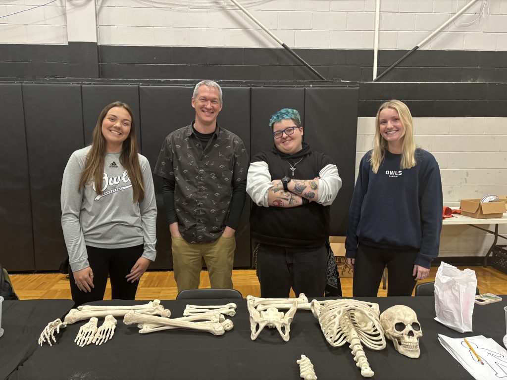 Dr. Hagey and departmental students behind a table with human bones.