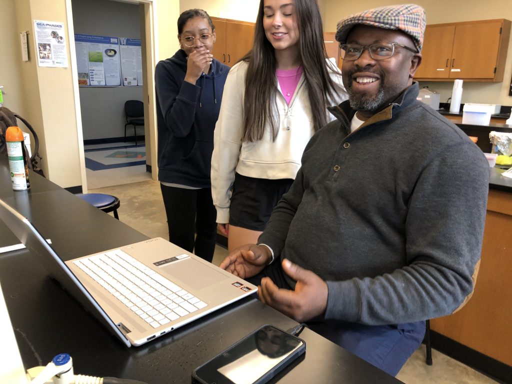 Dr. Onyeagucha, with two students, at a laptop on the lab bench.