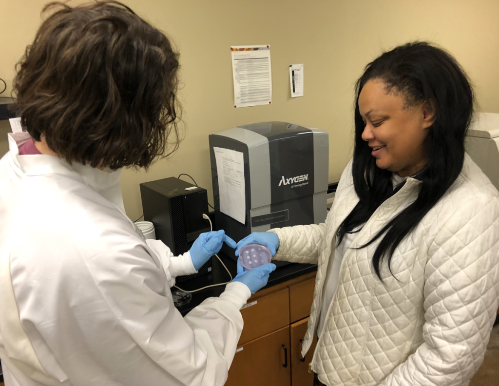 Dr. Davida Crossley examining a microbial plate with a student.