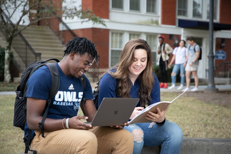 A male and female student study outside