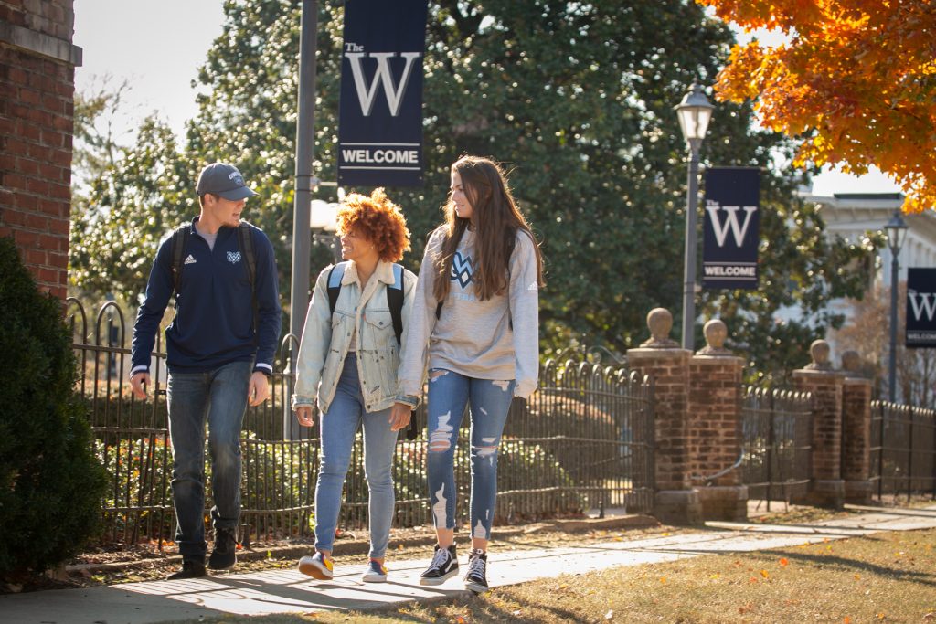 One male student and two female students walk on campus during the fall