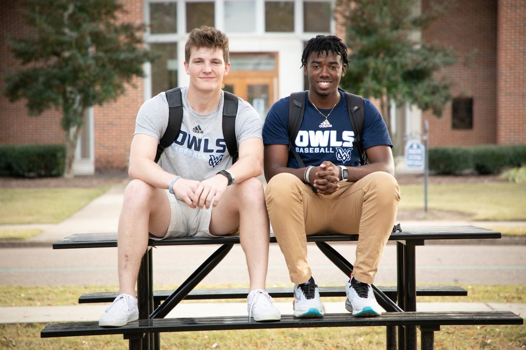 Two male students sit on a bench outdoors
