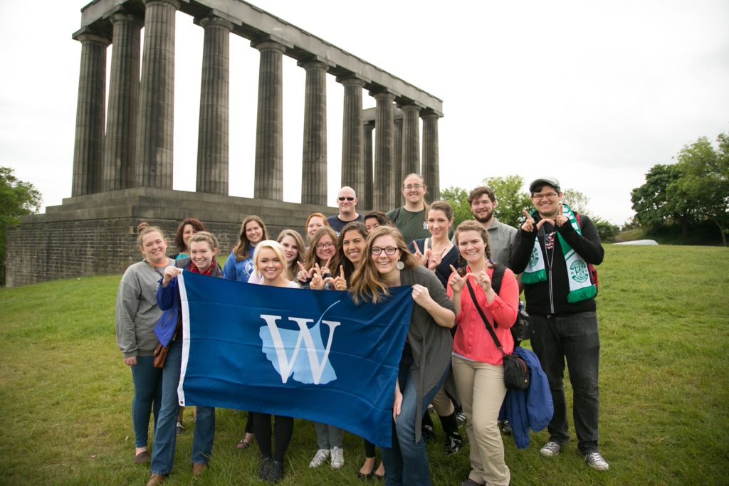 Students from The W in Scotland, holding a university flag