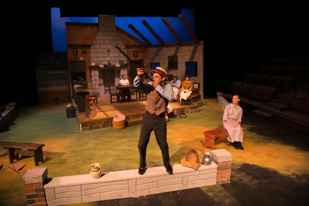 A man stands on a bench with a shotgun during a performance of Lughnasa