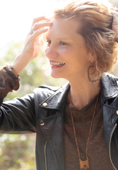 White woman with short blond hair holding her hand to her forehead