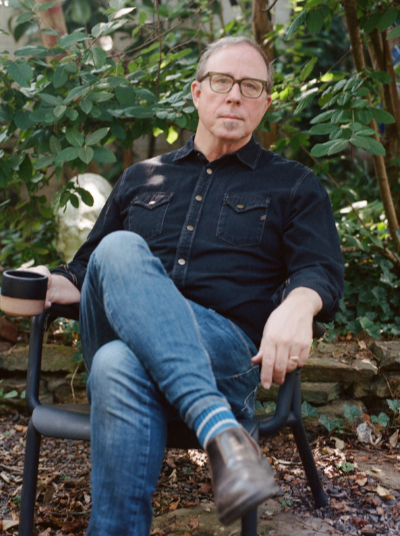 White man with glasses dark blue shirt and blue jeans